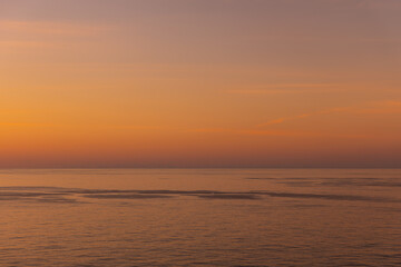 Obraz premium Vibrant image of Hazy Orange and pastel purple Caribbean sea Horizon calm reflective water beautiful peaceful background with copy space