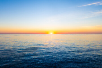 Obraz premium Tranquil fiery orange Sunrise Over ocean horizon on the Crystal Clear Caribbean Sea. Beautiful wide angle background with copy space.