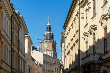 Fototapeta premium View of Krakow Town Hall Tower with clock rising above the historic buildings of Old Town under blue sky, Poland.