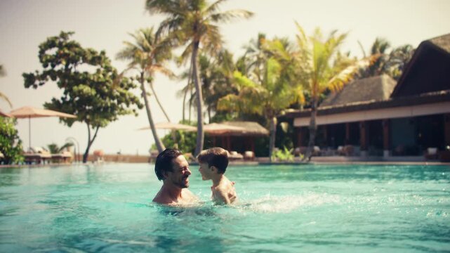 Happy father and son enjoy playful splashing and bonding in a luxurious resort pool