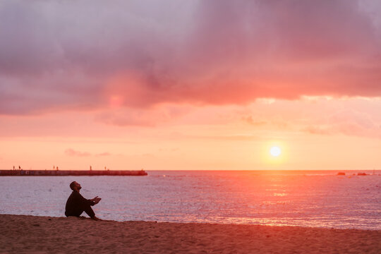 Young man enjoying solitude and inspiration on beach watching sunset