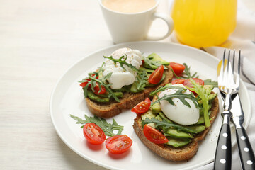 Tasty breakfast with avocado toasts and poached eggs served on light wooden table, closeup