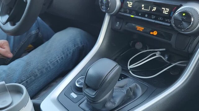 Male hand pulls the transmission selector lever to engage reverse gear. The scene focuses on vehicle control, driving operation, and interior detail of a modern car.