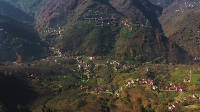 Aerial view of Batlama Valley in Giresun, Turkey, featuring traditional village houses and lush green mountains under sunlight in autumn.