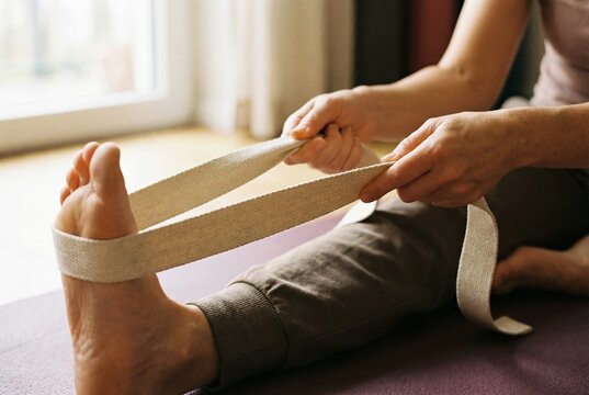 A close-up shot of a person using a yoga strap to deepen the stretch in their hamstring and leg.