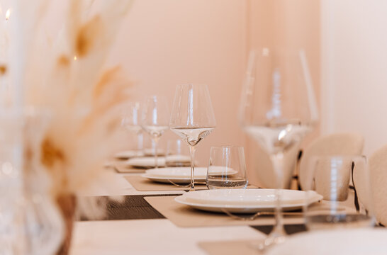Wine glasses and place settings on elegant banquet table in soft neutral interior