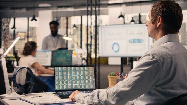 Professional man, business intel, visual data in office, analytics dashboard, performance metrics, forecasting reports, assisting with monetary data, resource allocation, and strategy planning.