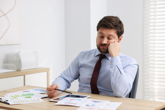 Unhappy businessman feeling fatigue at wooden table in office