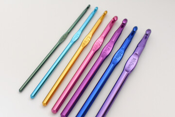 Fototapeta premium Top view of colorful crochet hooks arranged in a row. Creative DIY and craft concept for knitting, crochet projects, and handmade hobbies. 