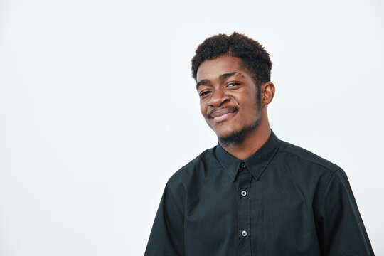 Young black man with dark skin wearing black shirt smiling confidently on white background. Portrait of African ethnicity male with short hair and casual style.