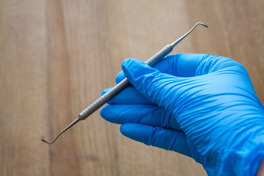 Hand in glove holding professional manicure and pedicure tool, stainless steel nail curette, podology