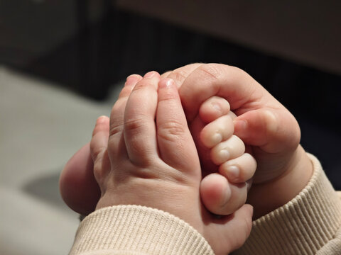 Eight month old baby holds his foot in his hands