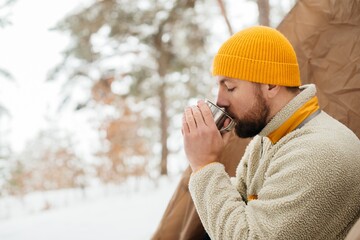 Man drinking hot beverage during winter solo hike © dsheremeta