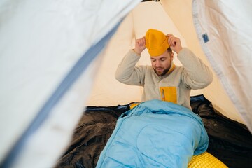 Man preparing for winter solo hike in camping tent © dsheremeta