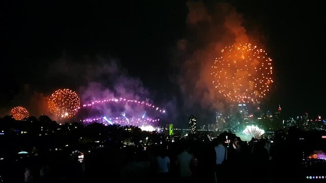 Australian crowd looking at New Years party fireworks display over Sydney Australia. Sydney's NYE is famous for being first to celebrate with massive fireworks on the Harbour Brid
