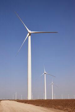 White wind turbines generating renewable energy at a wind farm under clear blue sky