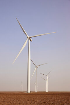 White wind turbines generating renewable energy in a desert landscape under clear skies