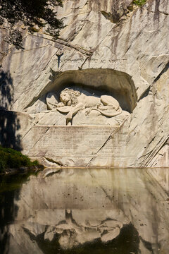 Majestic lion monument in Lucerne, Switzerland, reflecting in tranquil waters, honoring Swiss guards' bravery