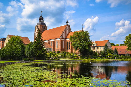 St. Anne&rsquo;s Church and historic houses reflected in a pond, Barczewo, Warmian-Masurian Voivodeship, Poland.
