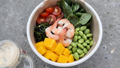 Healthy shrimp and mango poke bowl with edamame and fresh greens