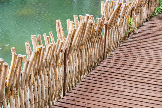 Woven willow railing beside artificial pond on wooden deck in Tomsk City Garden, Tomskaya Oblast