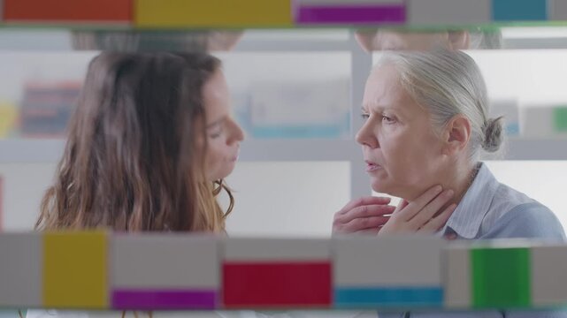 Female Pharmacist Recommending Throat Lozenges to Senior Woman