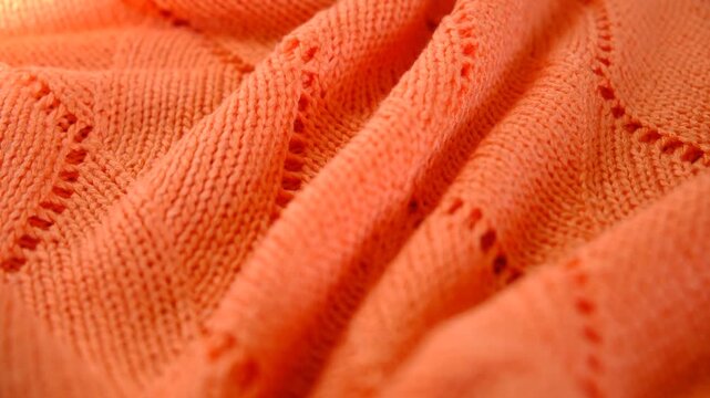 Coral color knitted fabric texture, mercerized. Product from wool. Reverse side. Handwork , Folded in waves and folds textiles, close up fabric. Detailed warm yarn background. Cardigan, sweater