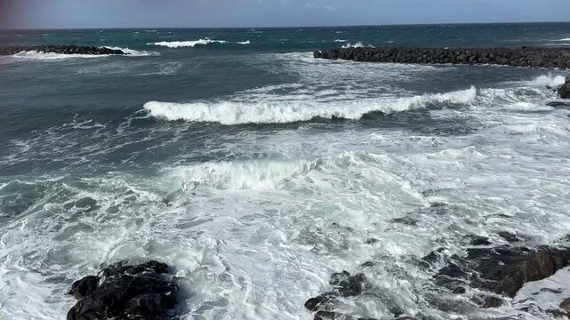 Rugged volcanic rocky coastline with foamy Atlantic waves and black lava cliffs