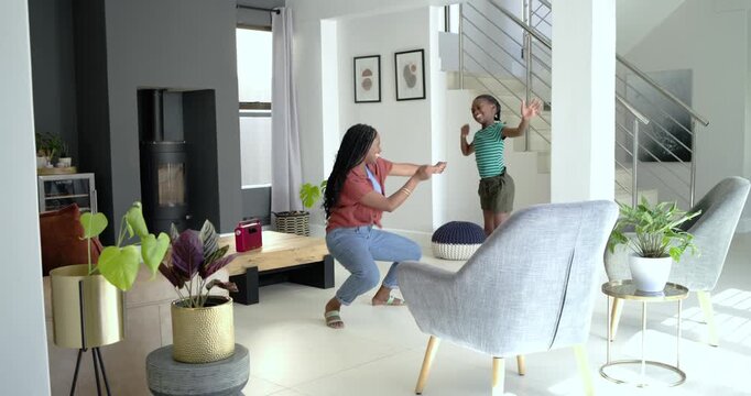 African American mom and daughter dancing to red speaker music at home copying spinning bonding