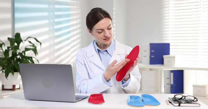 Orthopedist recommending foot insoles at table indoors