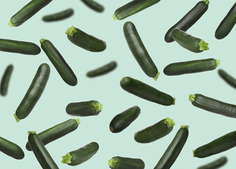 Fresh zucchinis falling against light turquoise background