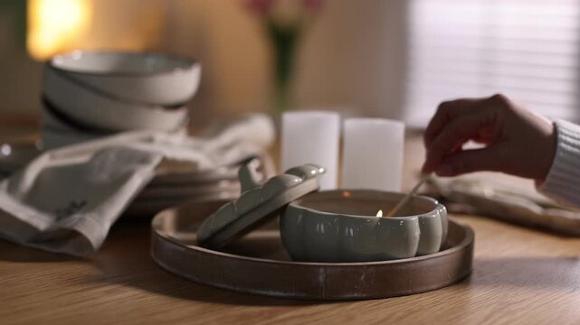 Woman lighting up beautiful candles at dining table indoors, closeup