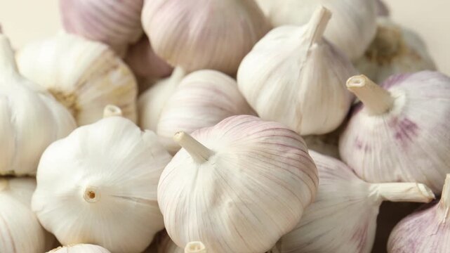 Fresh garlic bulbs as background, closeup. Camera spinning