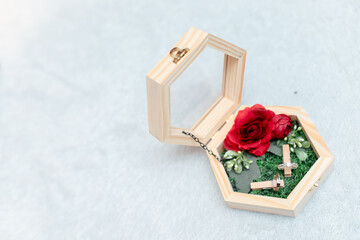 Elegant wooden jewelry box with red rose and wedding rings on green velvet