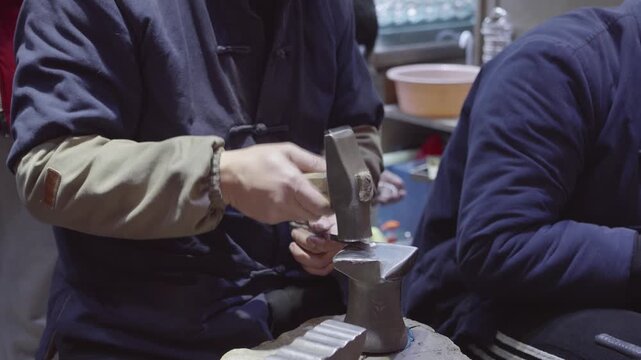 Close up view of handcrafting of jewelry. Man hammering a piece of silver or precious metal into a metal blank, 4k slow motion footage.