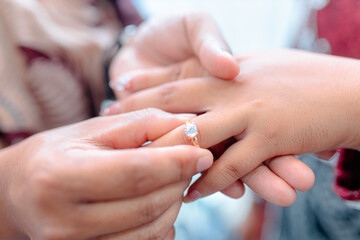 Tender moment of putting engagement ring on woman's finger