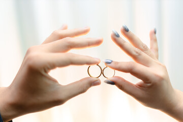Two hands holding golden wedding rings in elegant gesture