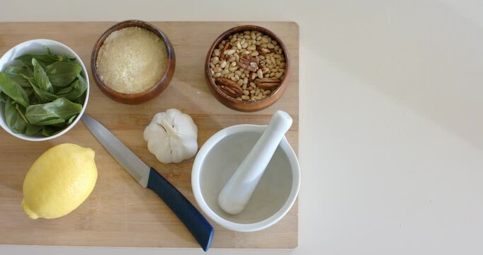 Camera is zooming to center cutting board with basil, cheese, garlic on counter, copy space