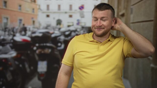 Man rubbing neck with hand on a busy street beside parked scooters, looking sideways with a shy grin; sheepish embarrassed smile.