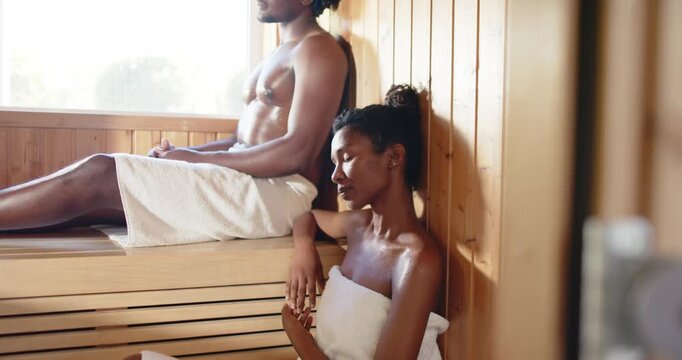 African American couple reacting to cam pulling back, sharing private sauna moment wearing towels
