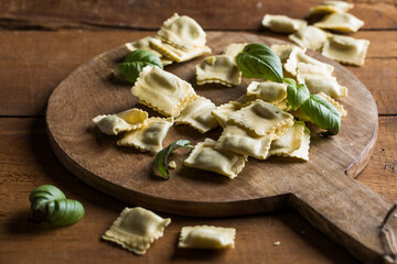 Fototapeta premium Fresh raw ravioli pasta on a rustic wooden table, natural light, artisanal food styling
