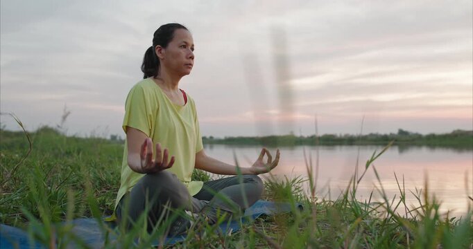 Asian woman practicing yoga in lotus pose on mountain at sunset, mental resilience and nature therapy, authentic spiritual wellness and bio-harmony in cinematic lighting.