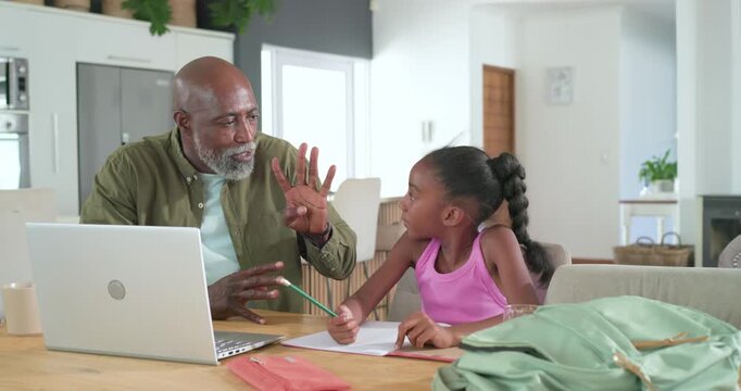 African American senior man guiding child after girl pausing, counting steps with pencil at kitchen