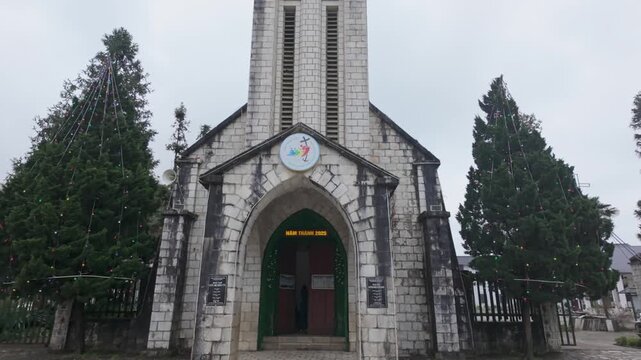 A view of the stone facade of the Sapa, L&agrave;o Cai, Vietnam, with Christmas trees on either side of the entrance.
