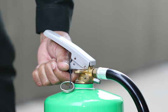 Fire extinguisher safety emergency training hand handle hose pin, closeup of person gripping trigger for workplace fire prevention and readiness
