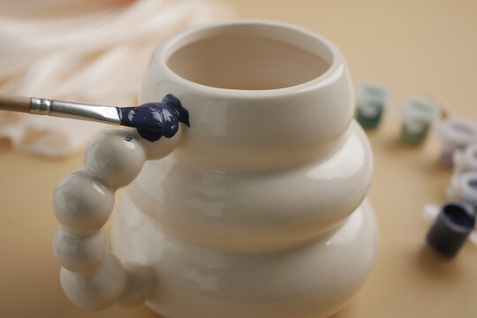 Crafting a ceramic mug with brush and paint