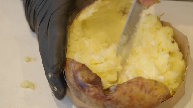 Making a baked potato with butter and sour cream