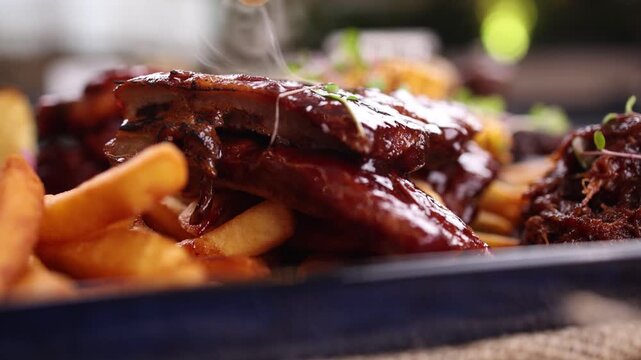 Delicious BBQ ribs and pulled pork served with crispy french fries on a dark plate