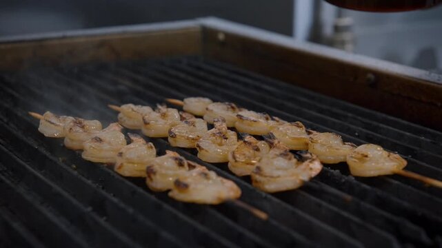 Chef basting shrimp skewers on a hot grill with a brush, creating a delicious meal
