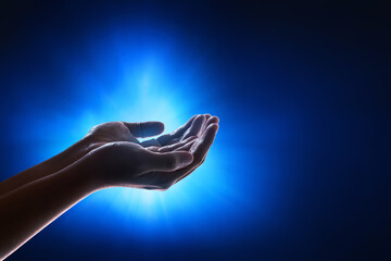Hands of young asian muslim man praying on dark blue background, eid adha mubarak concept